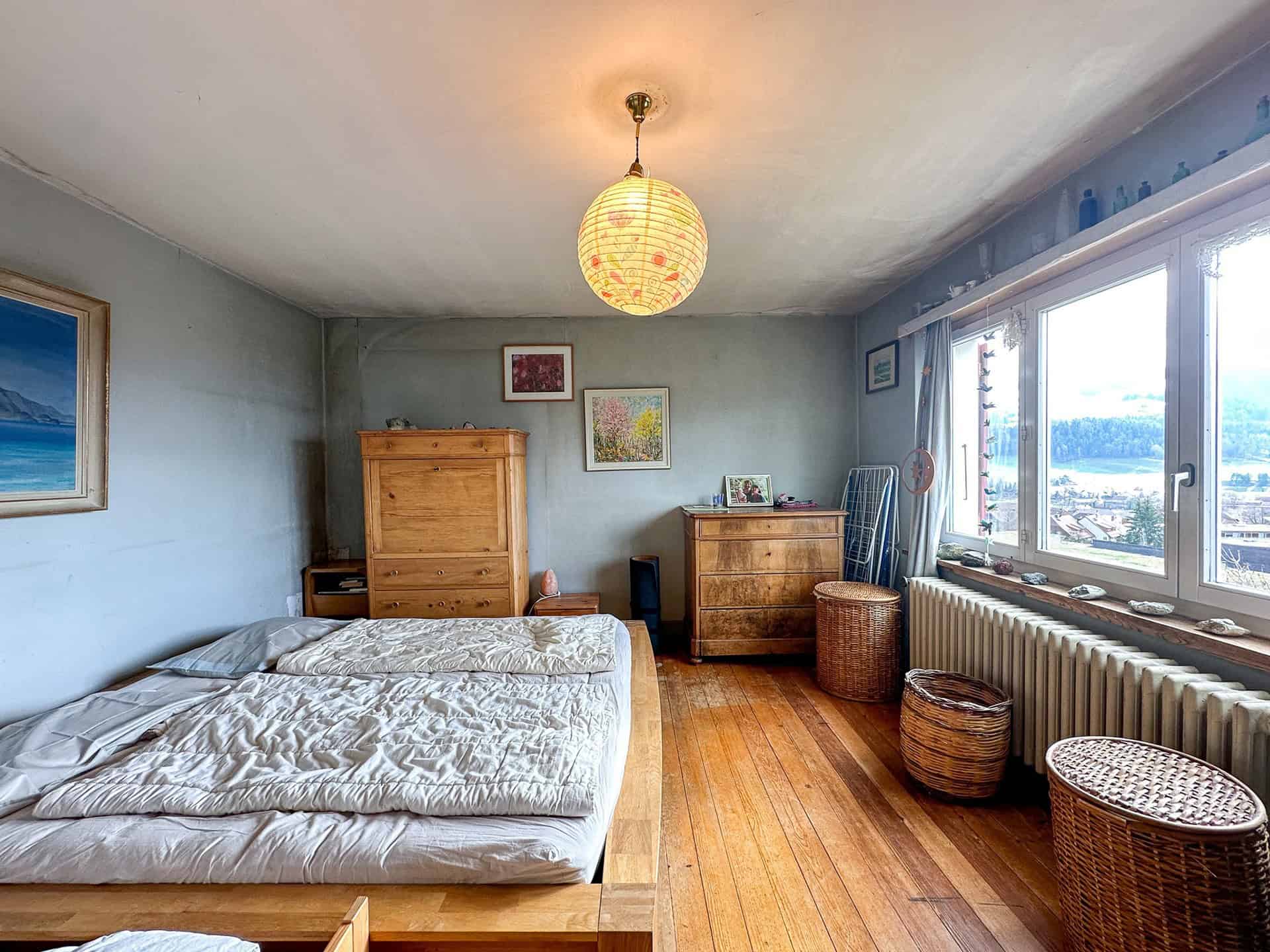Schlafzimmer mit Holzfußboden und großem Fenster