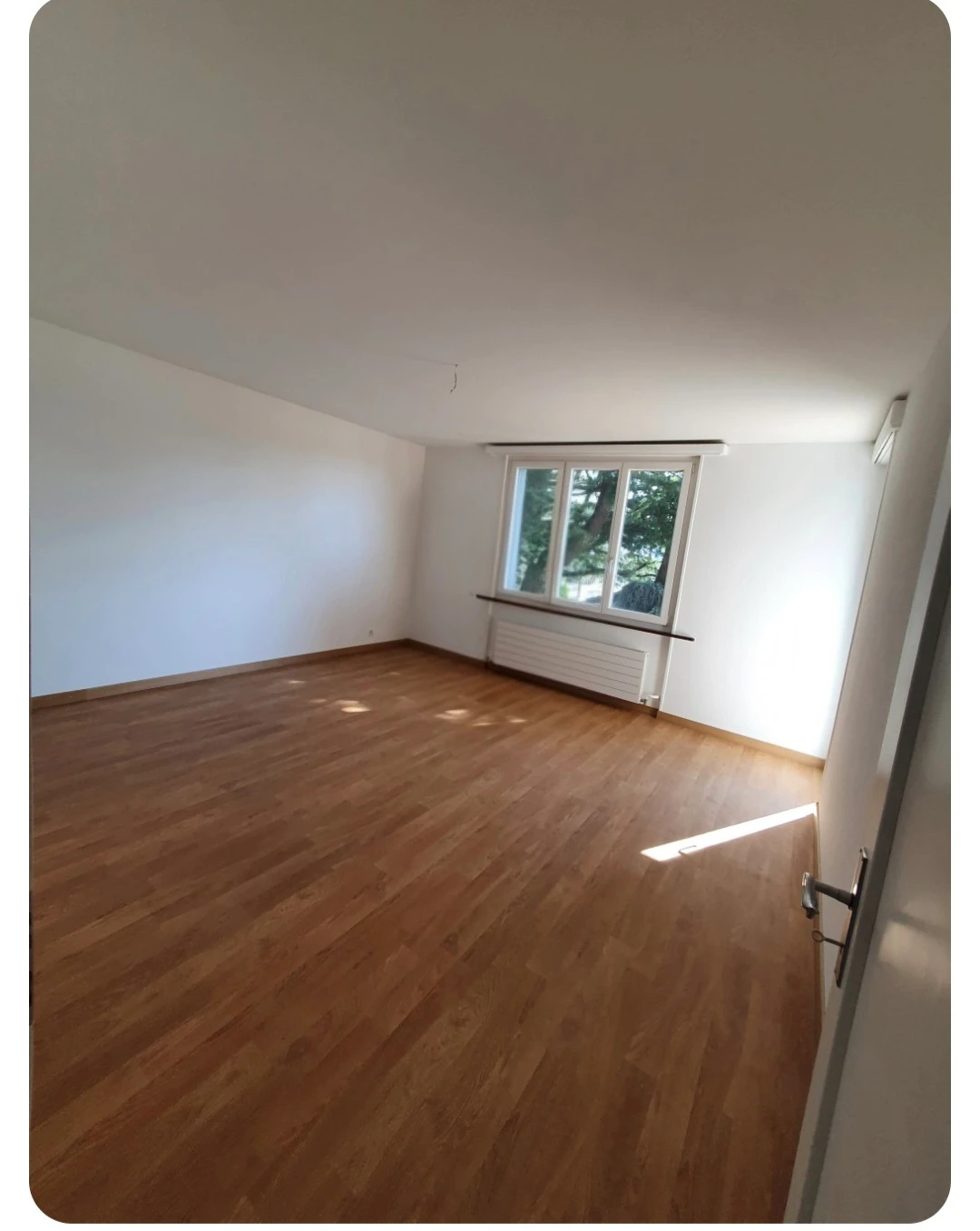 Leerer Wohnraum mit Parkett und Fenster