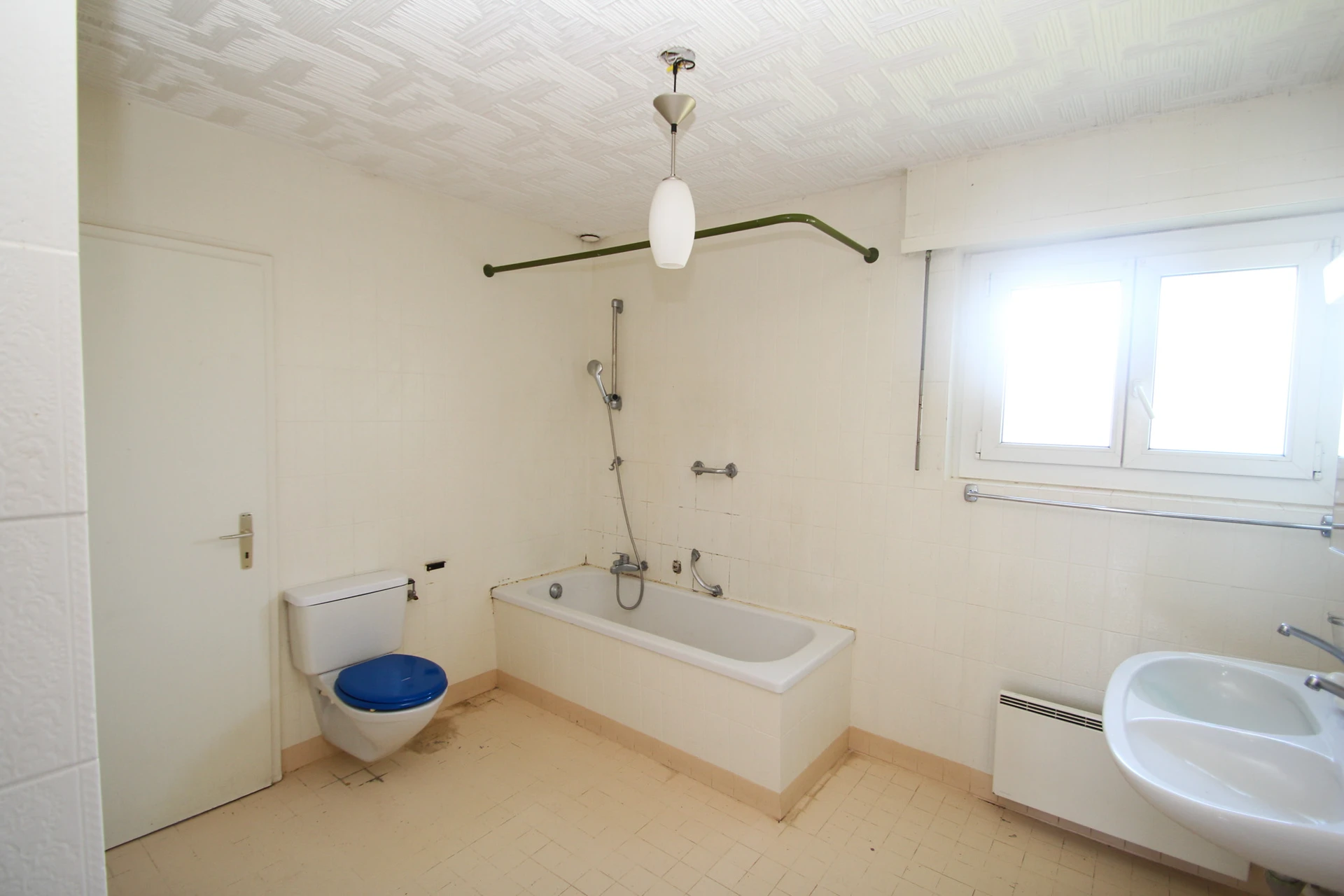Ein schlichtes, älteres Badezimmer mit Badewanne, WC und Waschbecken