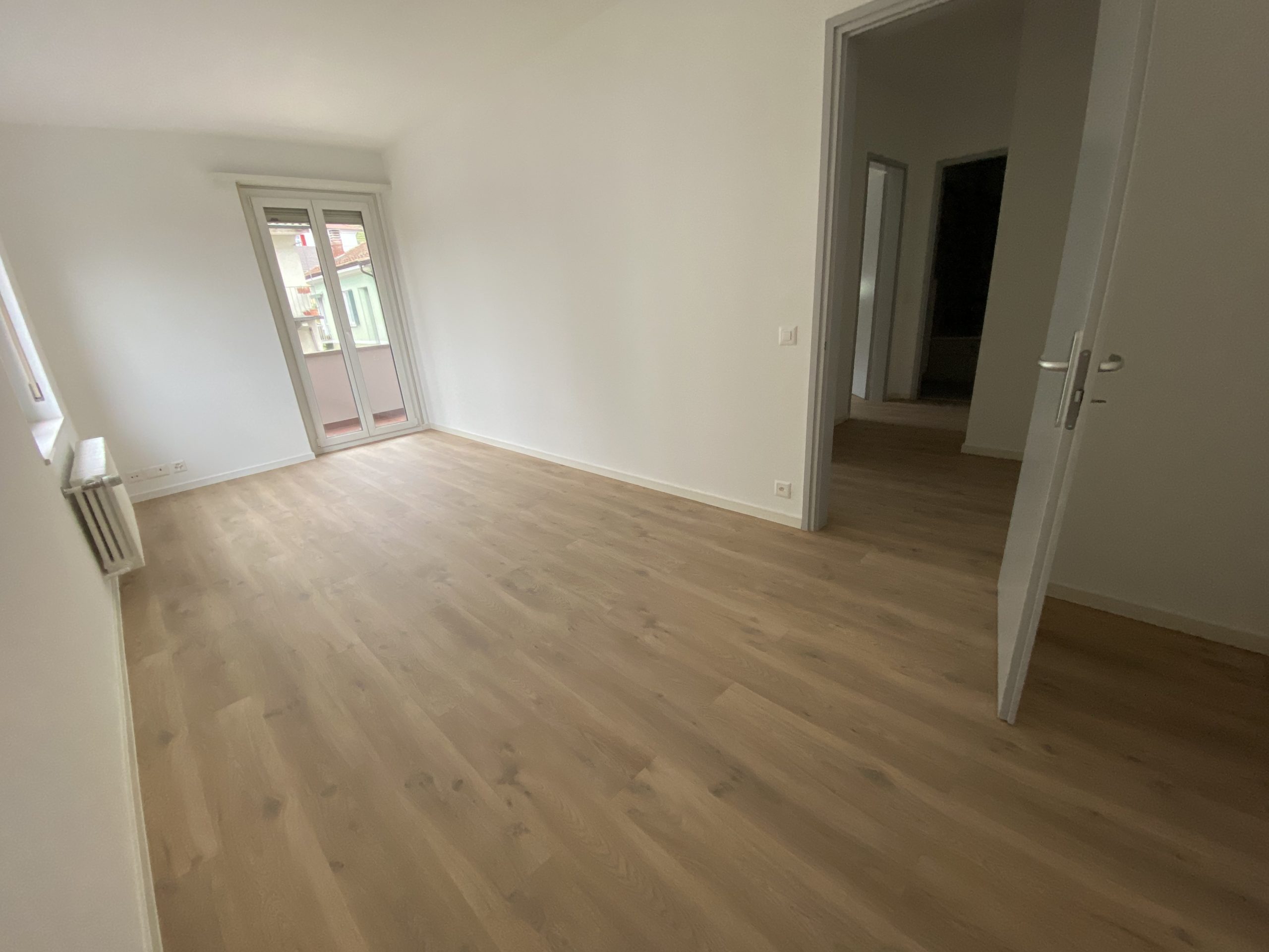 Leerer, heller Wohnraum mit Balkonzugang