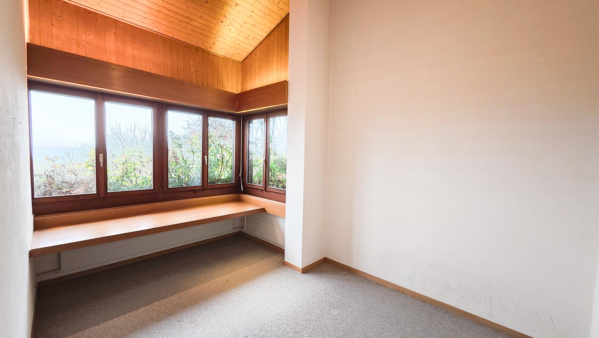 Heller Raum mit großer Eckverglasung und Holzdecke