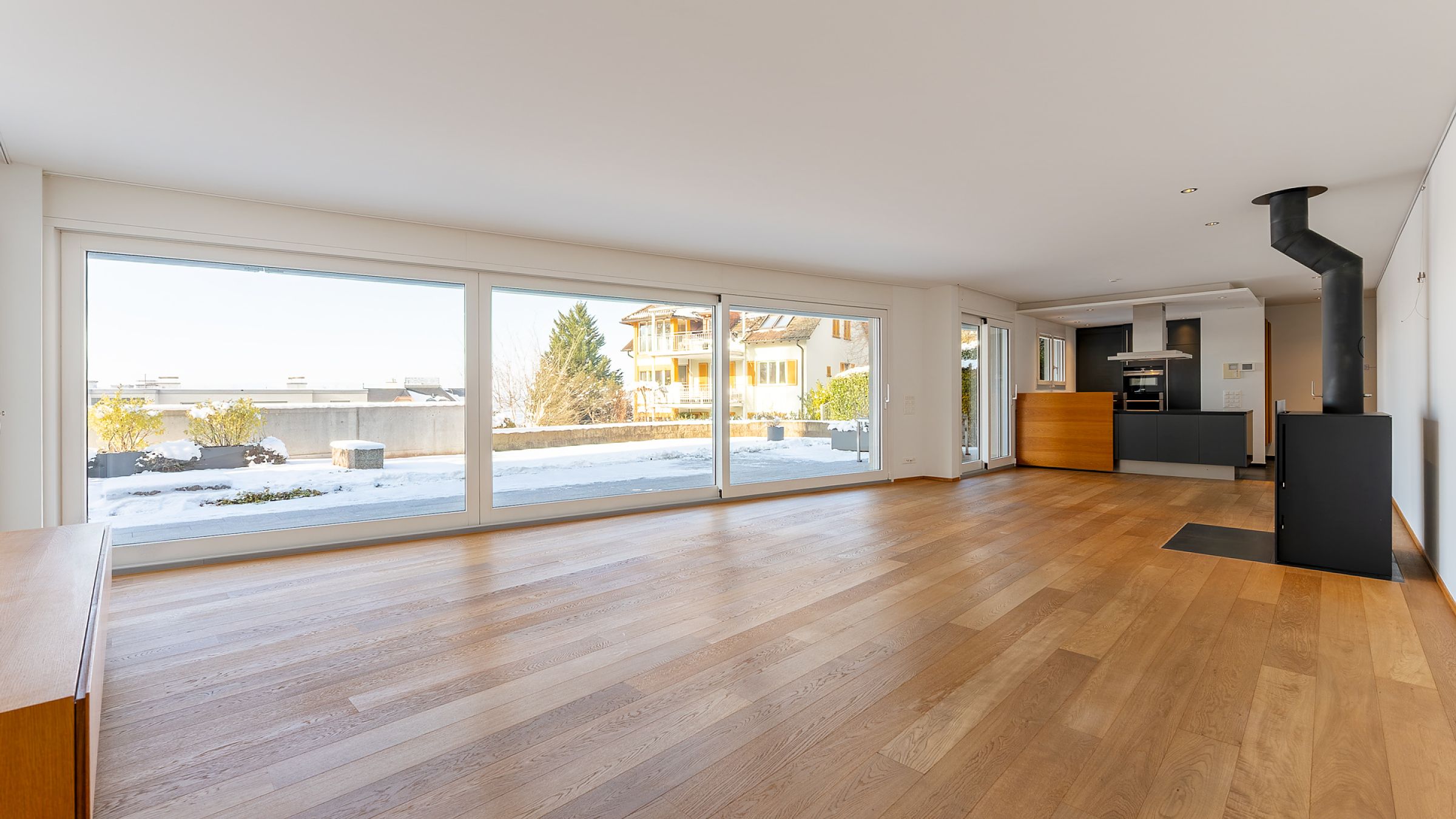 Großer heller Wohnbereich mit Panoramafenstern und Kaminofen