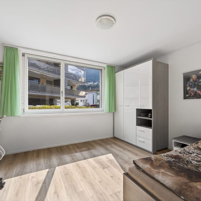 Helles Schlafzimmer mit großem Fenster und Schrank