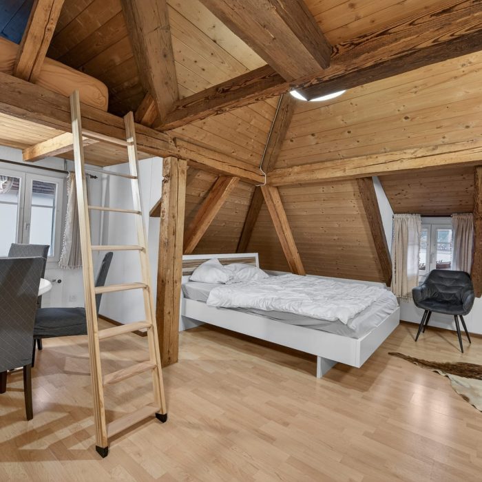 Dachzimmer mit Bett und Holzbalken