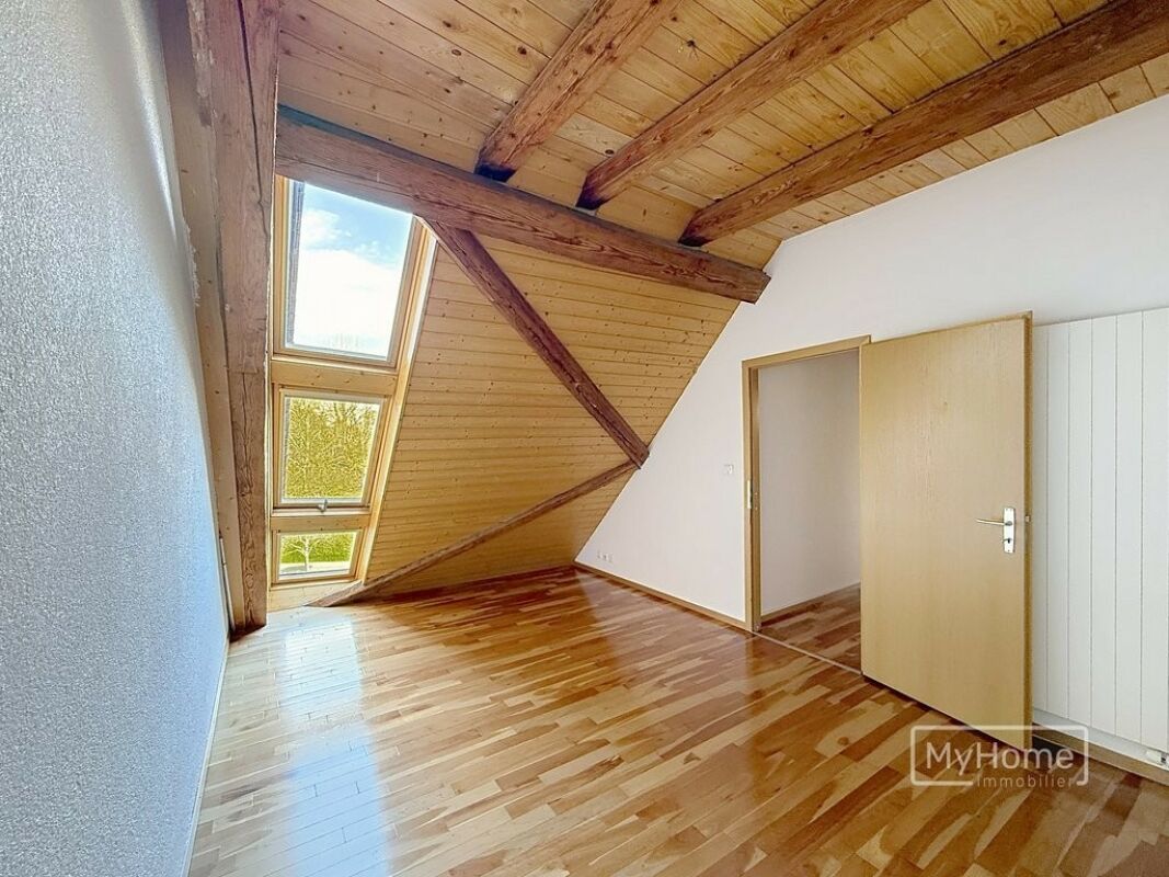 Dachzimmer mit sichtbaren Holzbalken und Dachfenstern