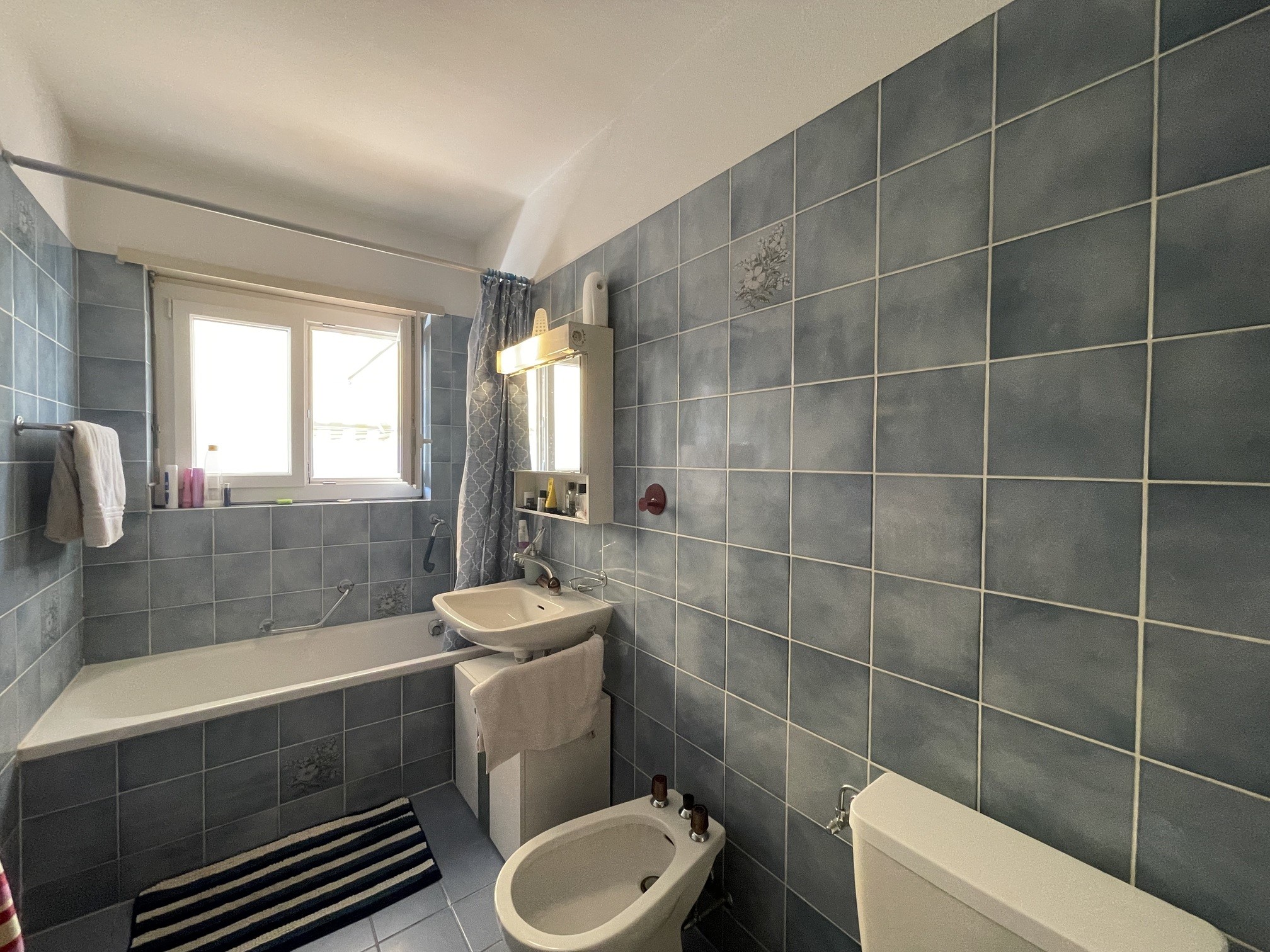 Badezimmer mit blau gefliesten Wänden und Badewanne
