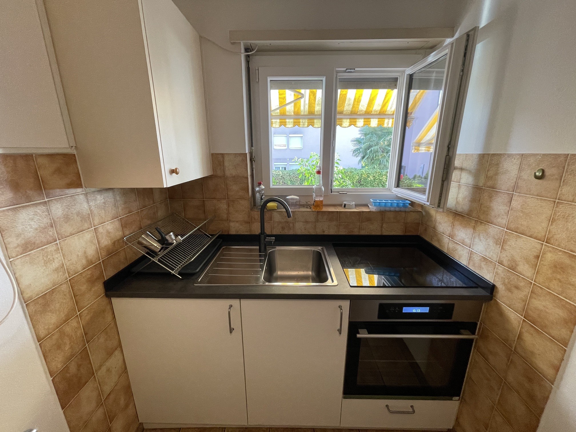 Kleine Küche mit Fenster und schwarzer Arbeitsplatte