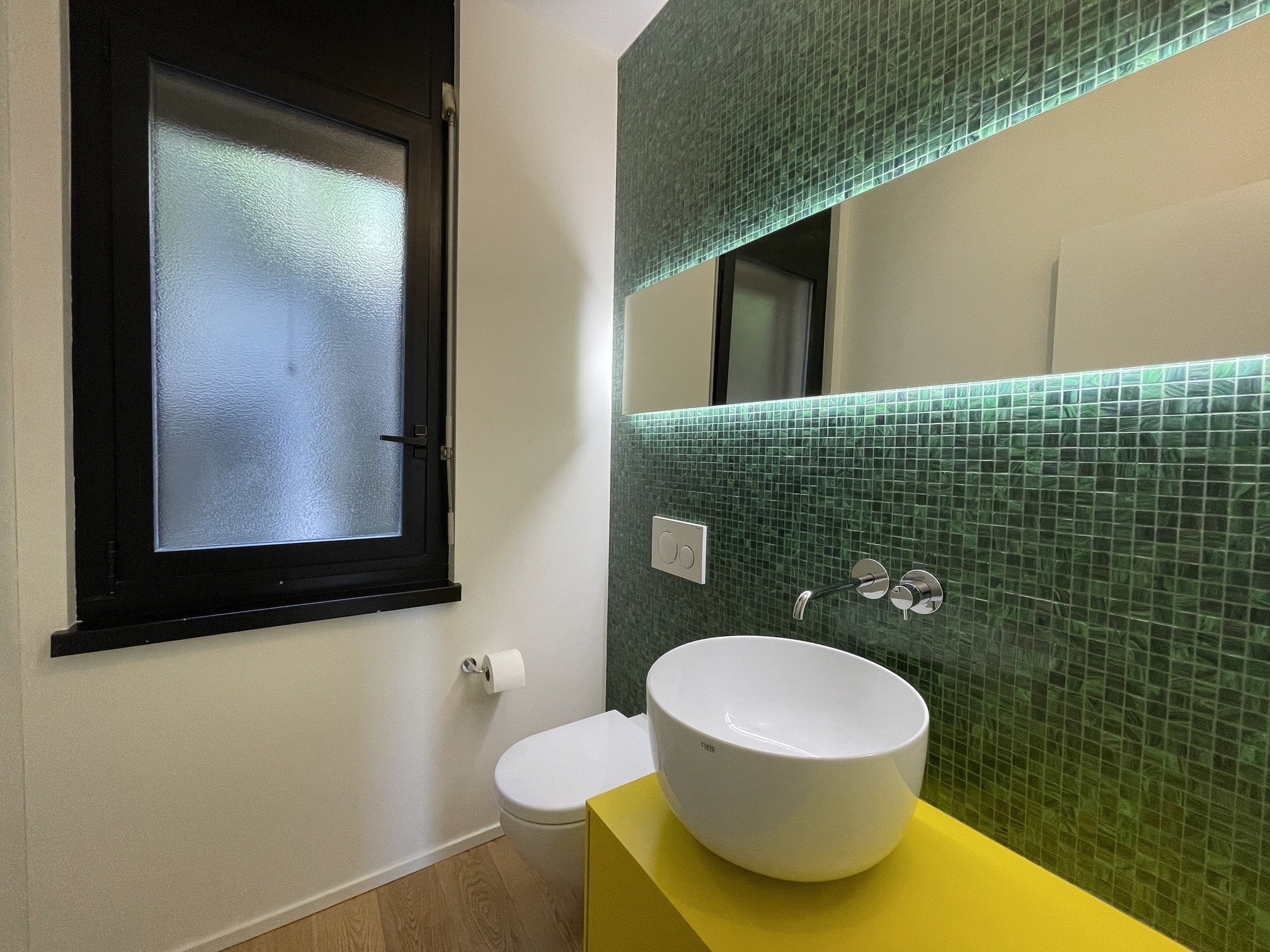 Modernes Gäste-WC mit grünem Mosaik und farbigem Waschtisch