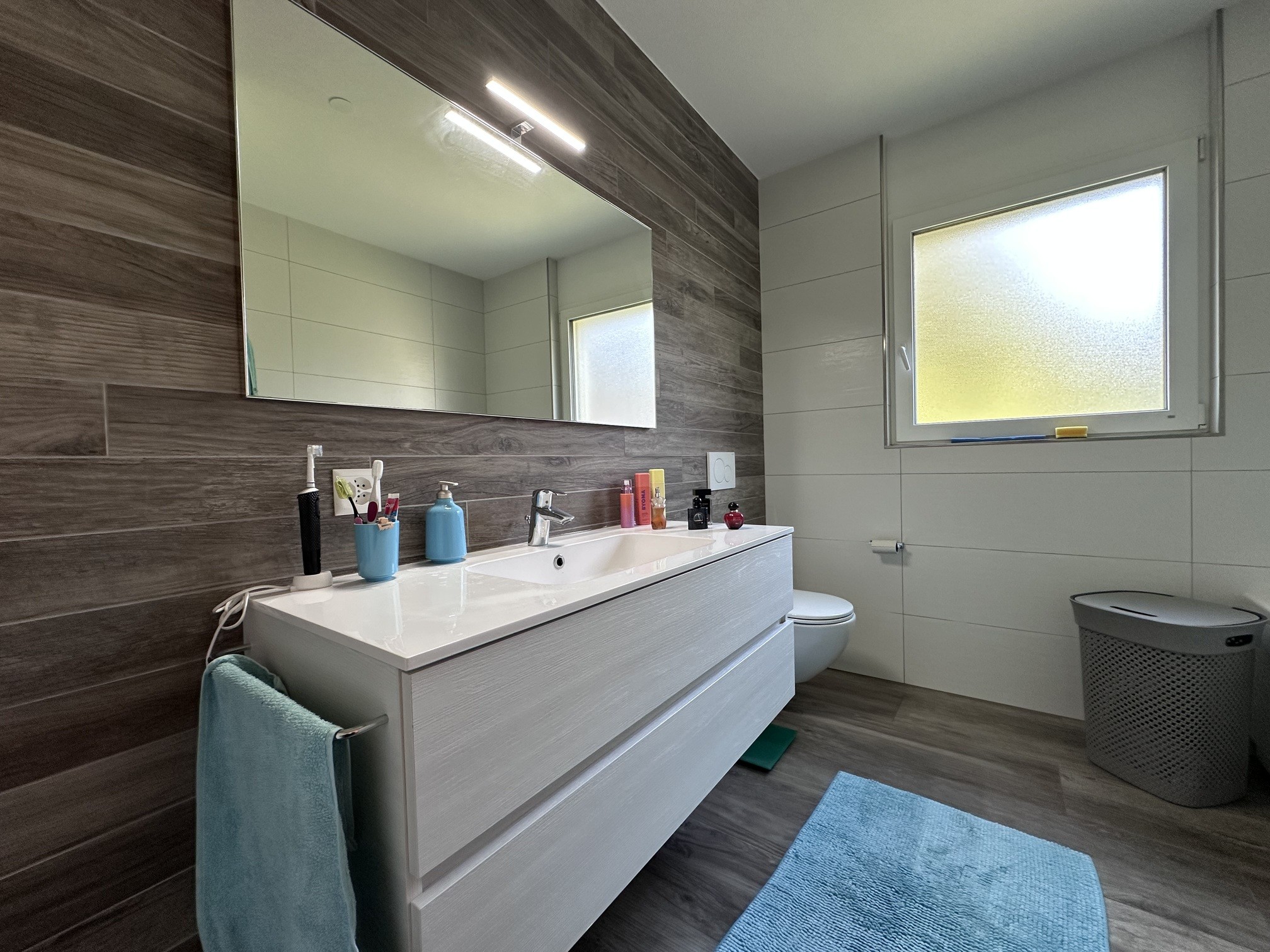 Modernes Badezimmer mit Holzoptik und hellem Waschtisch