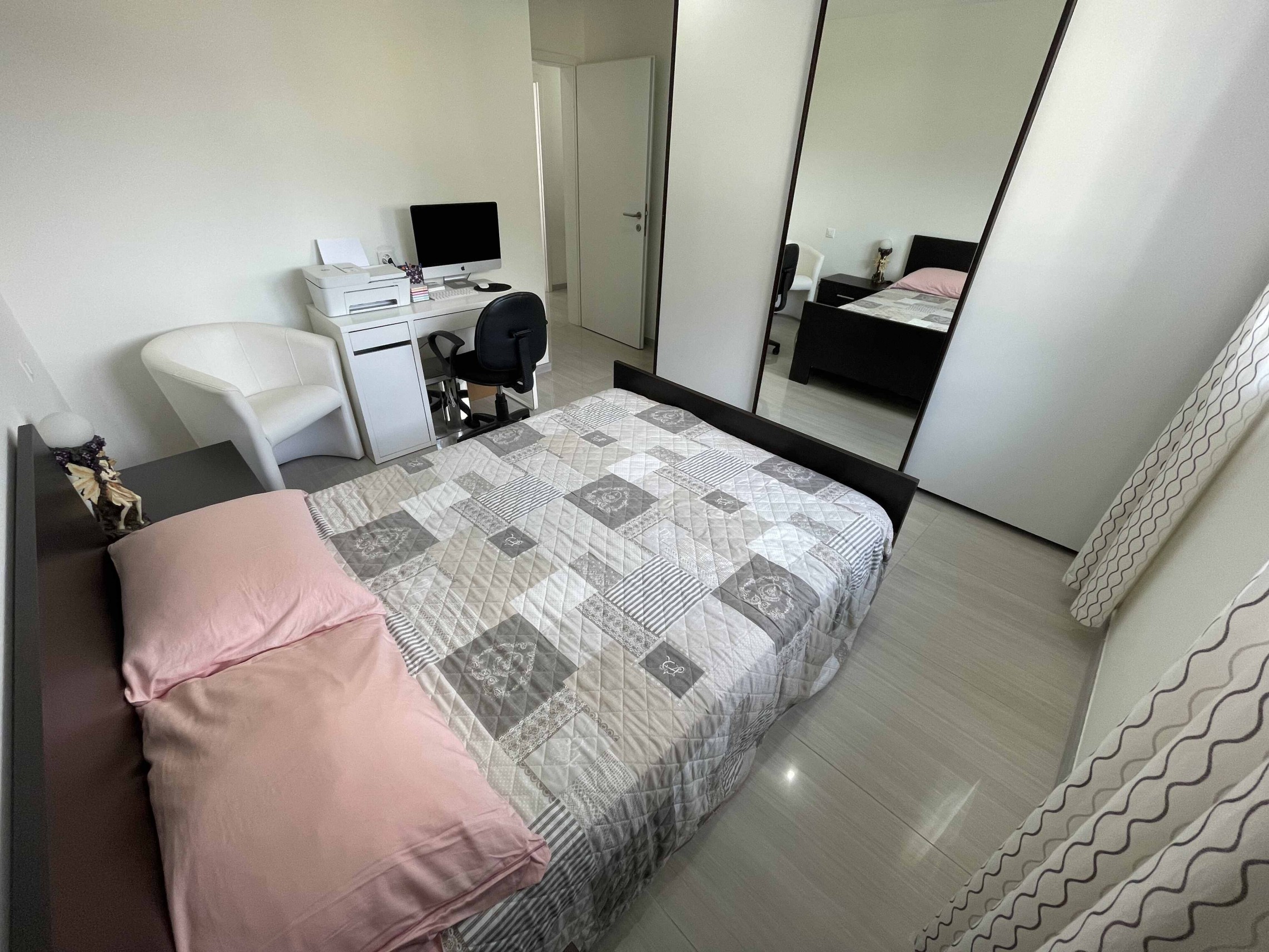 Helles Schlafzimmer mit Bett und Arbeitsbereich