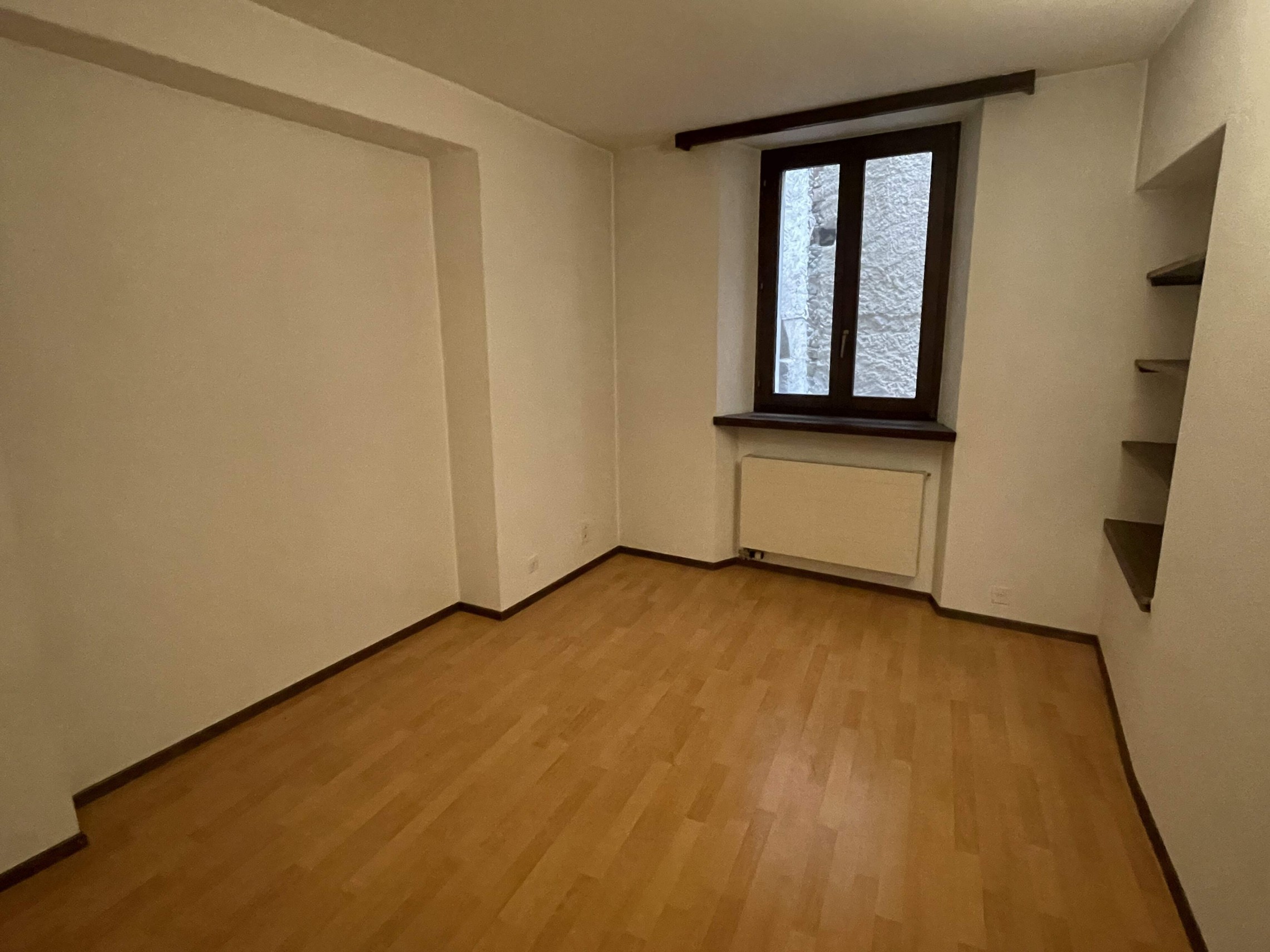 Leerer Raum mit Fenster und Parkettboden
