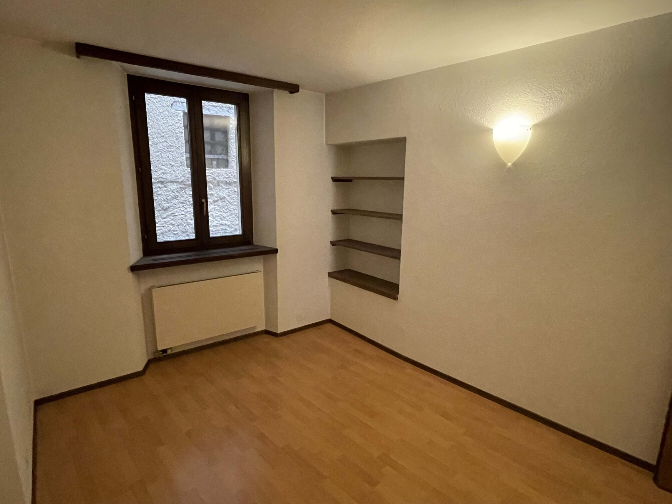 Kleines leeres Zimmer mit Holzfußboden