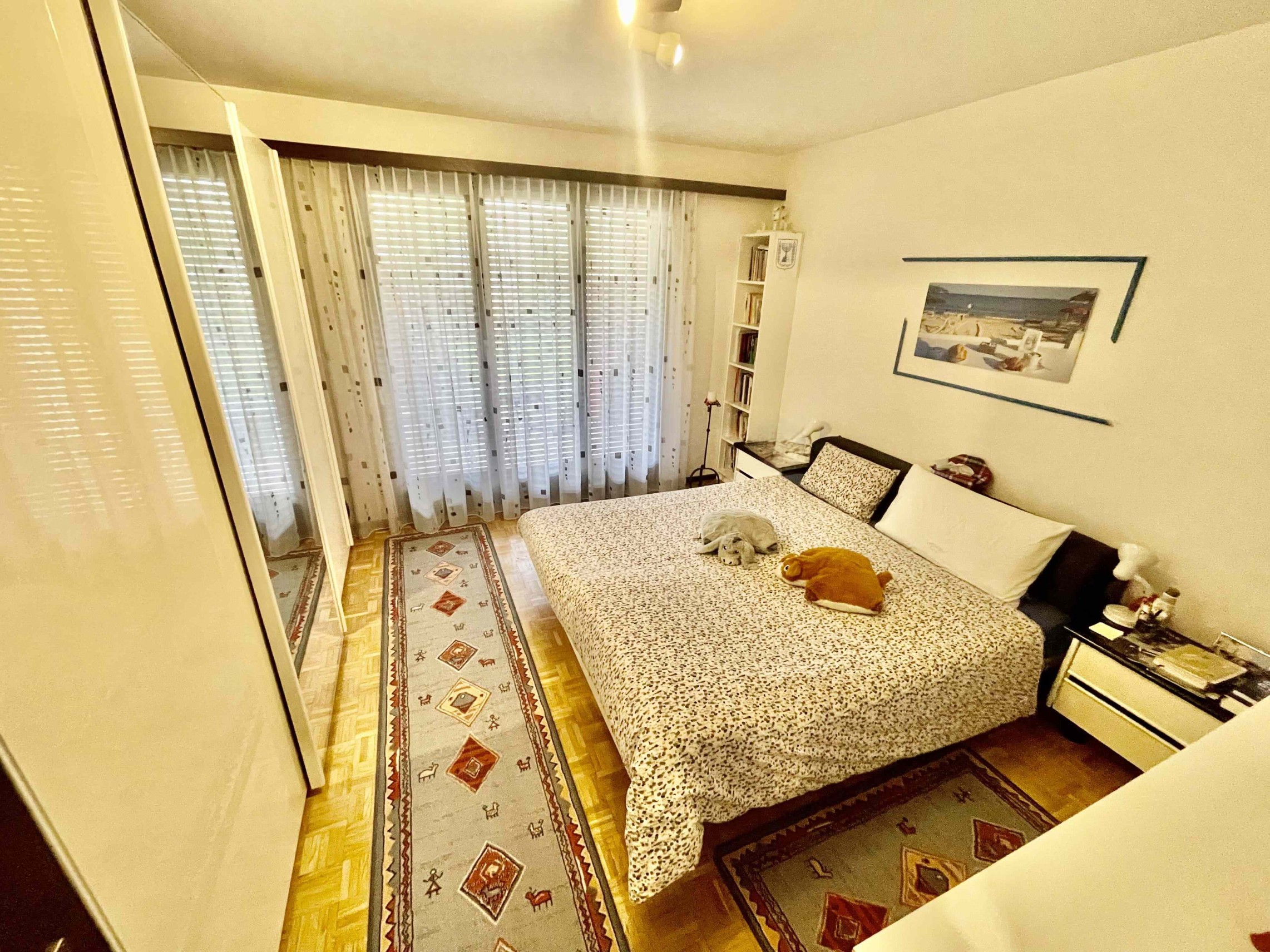 Schlafzimmer mit Bett und Balkonfenstern