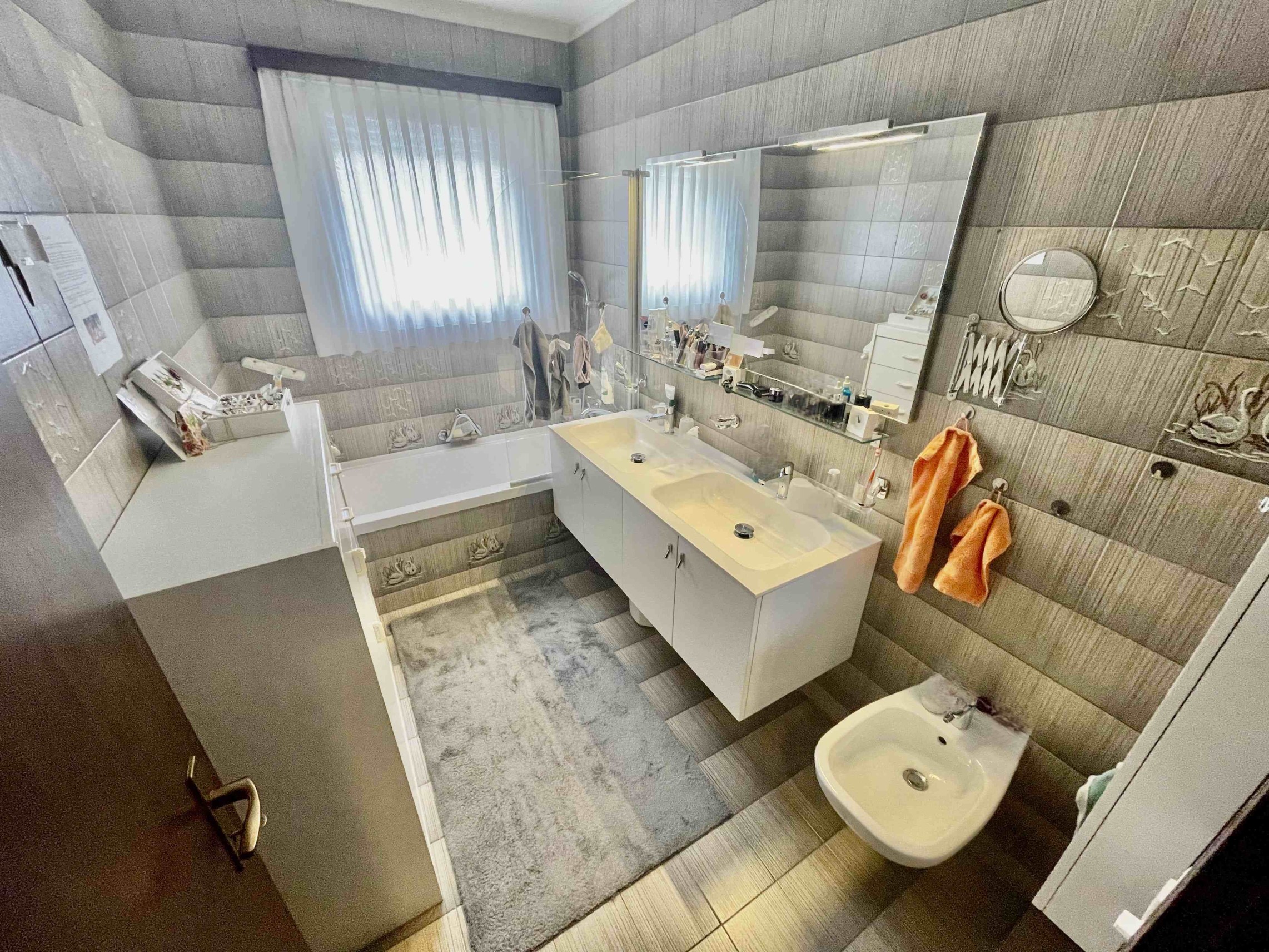 Modernes Badezimmer mit Badewanne, Doppelwaschtisch und großem Spiegel