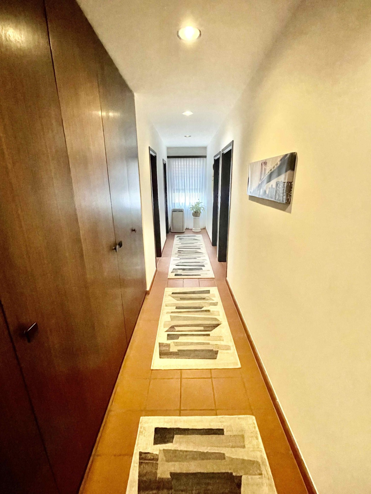 Langer Flur mit Einbauschrank und Fenster am Ende