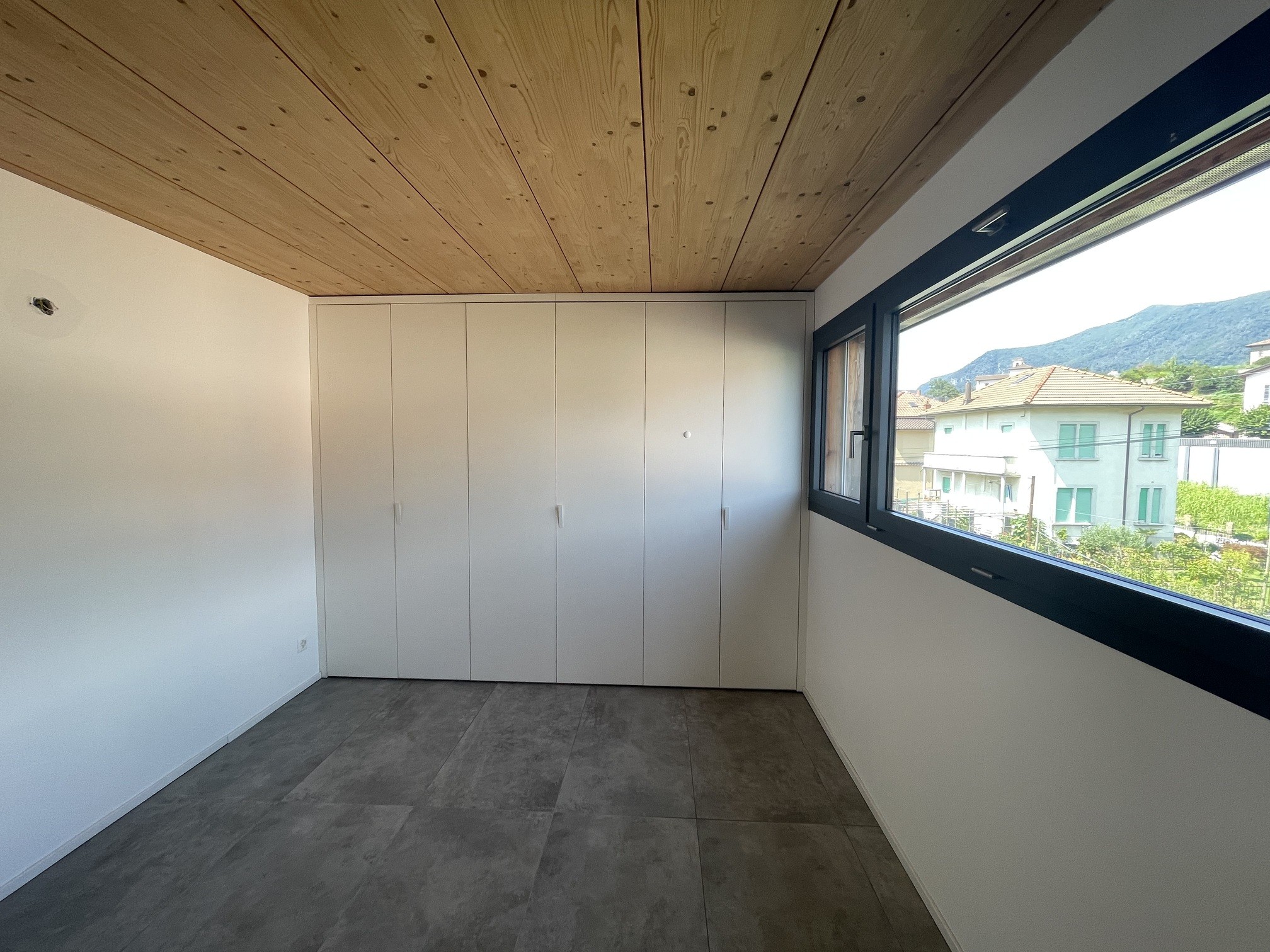 Modernes Schlafzimmer mit Naturholzdecke und großem Fenster