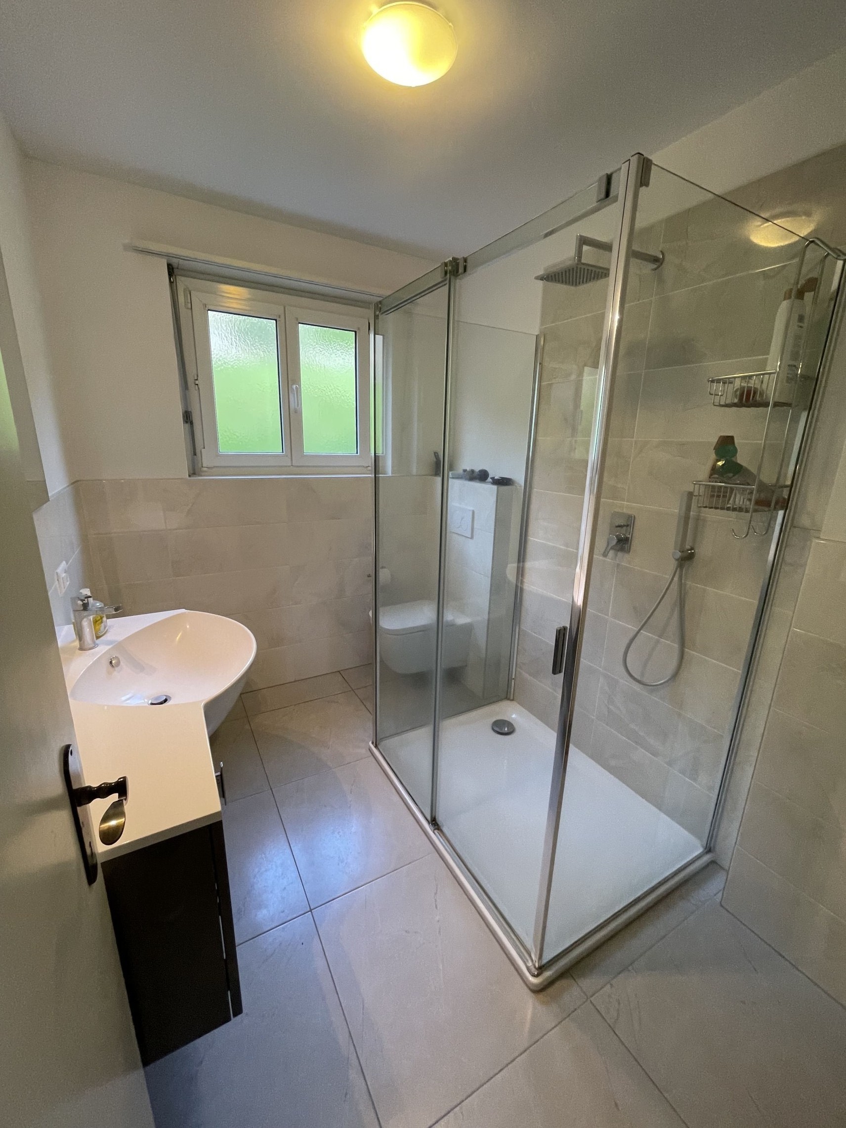 Modernes Badezimmer mit Glasdusche und Fenster