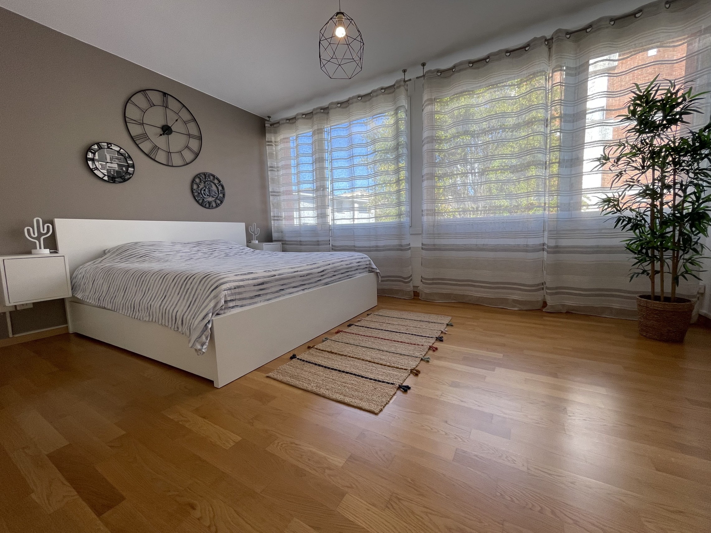 Helles Schlafzimmer mit weißem Bett und großen Fenstern