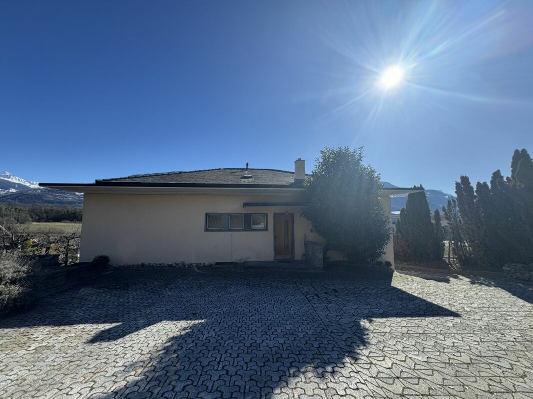 Außenansicht eines eingeschossigen Hauses mit gepflasterter Zufahrt
