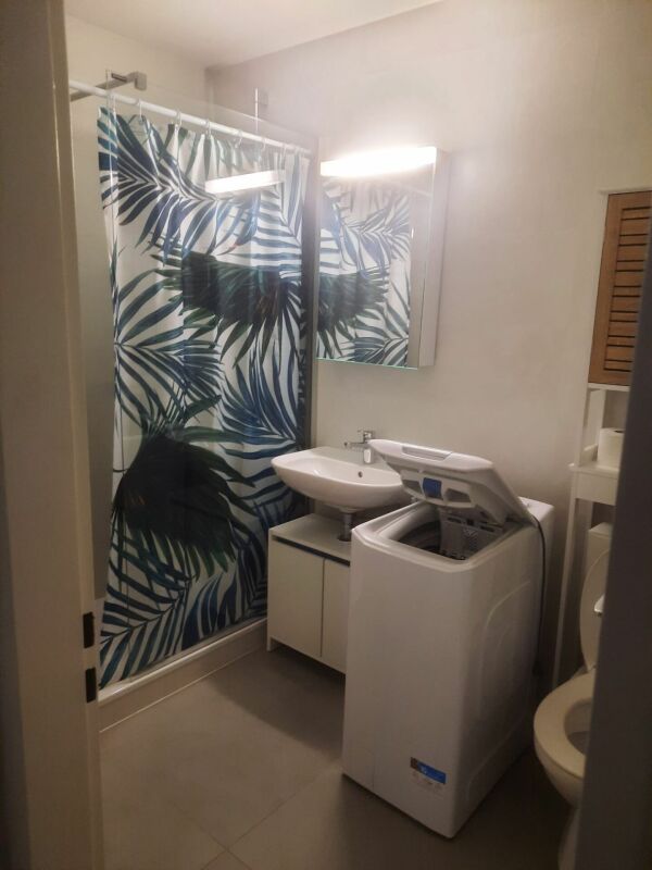 Kleines Badezimmer mit Duschvorhang und Waschmaschine