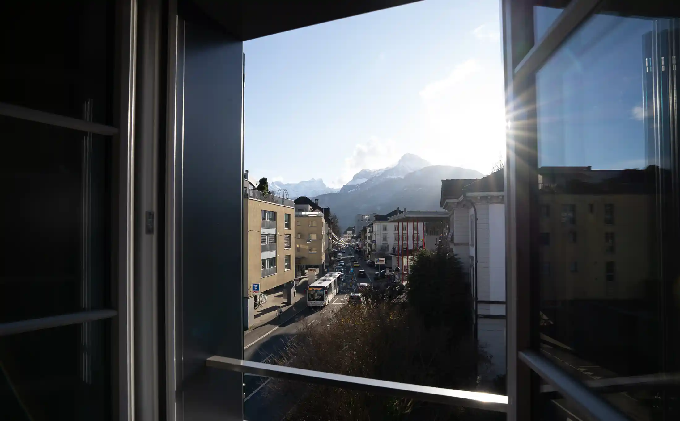 Blick durch ein Fenster auf Stadt und Berge