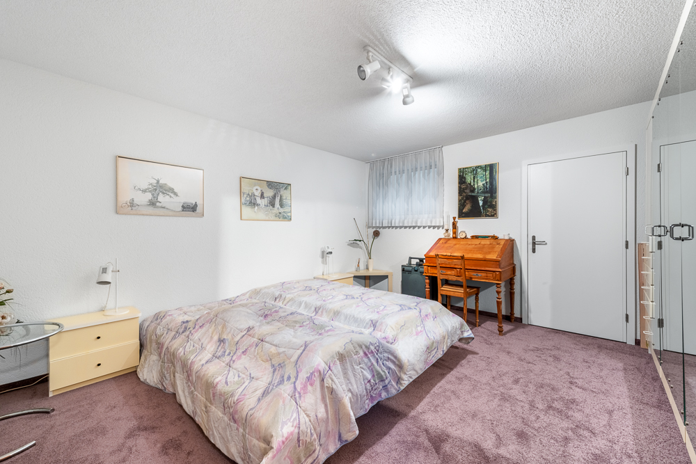 Schlafzimmer mit Teppichboden und Schreibtisch