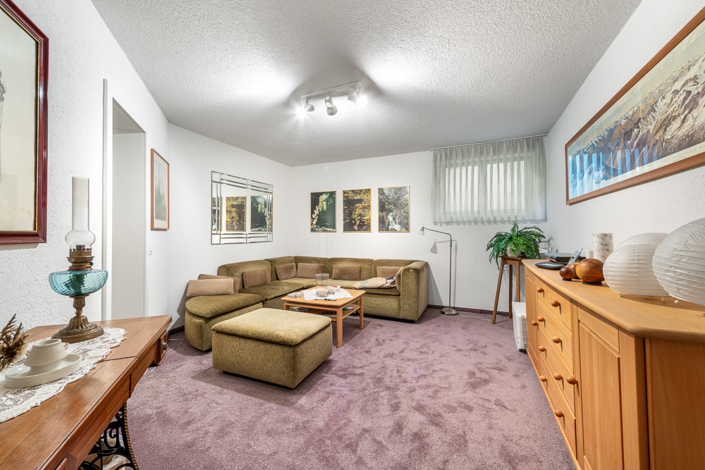 Gemütliches Wohnzimmer mit Ecksofa und Teppichboden