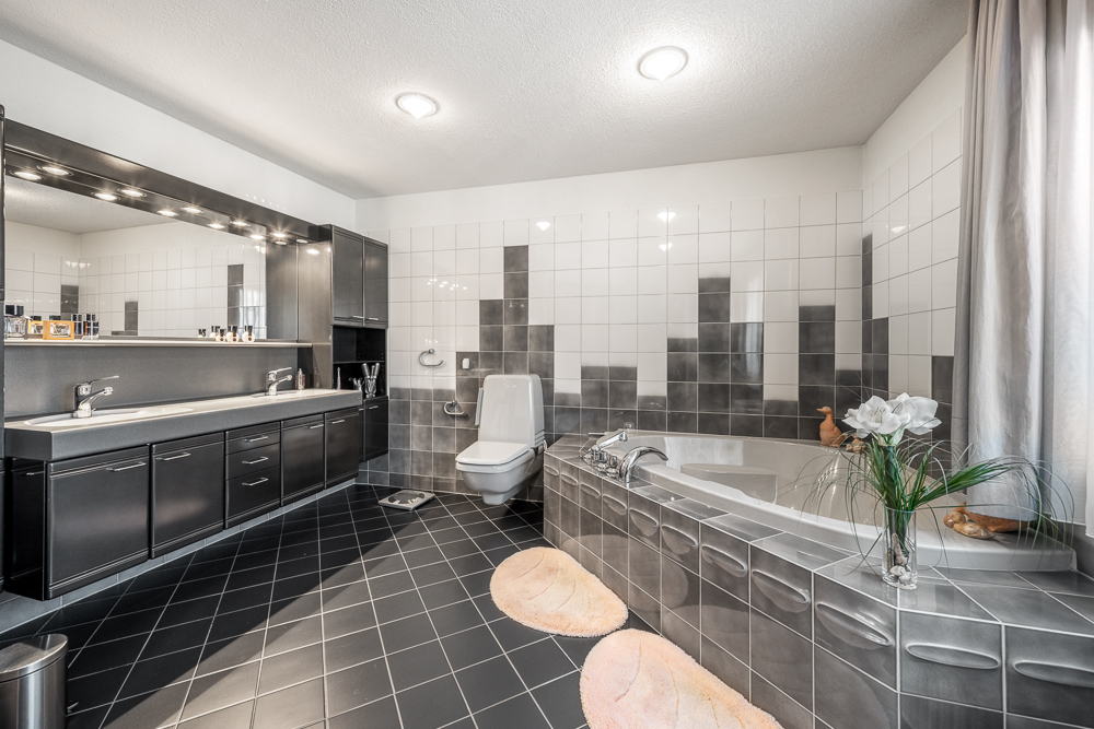 Modernes Badezimmer mit dunklen Fliesen und Badewanne
