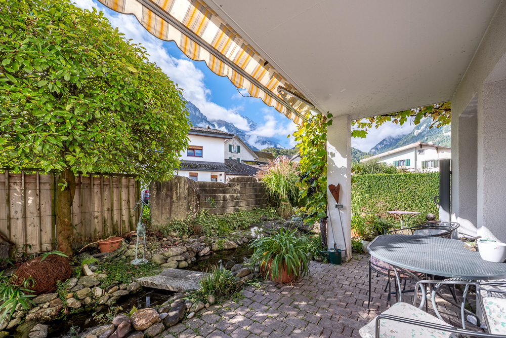 Überdachte Gartenterrasse mit Teich und Bergblick
