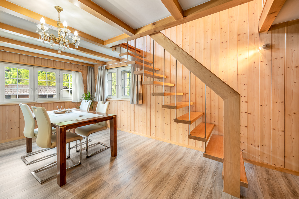 Essbereich mit Holzvertäfelung und offener Treppe