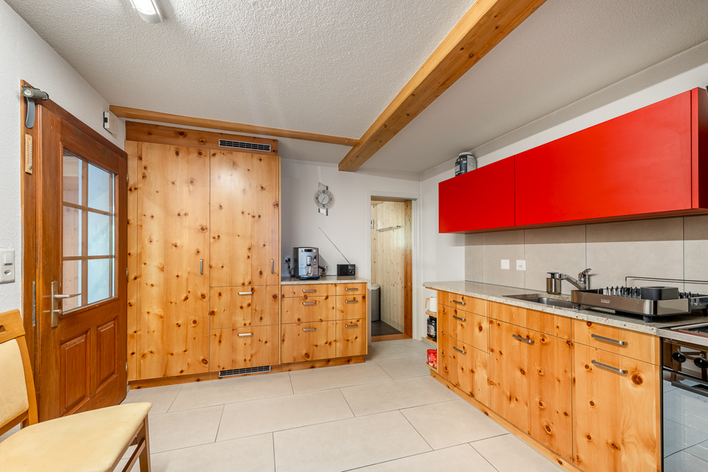 Moderne Küche mit Holzfronten und roten Oberschränken