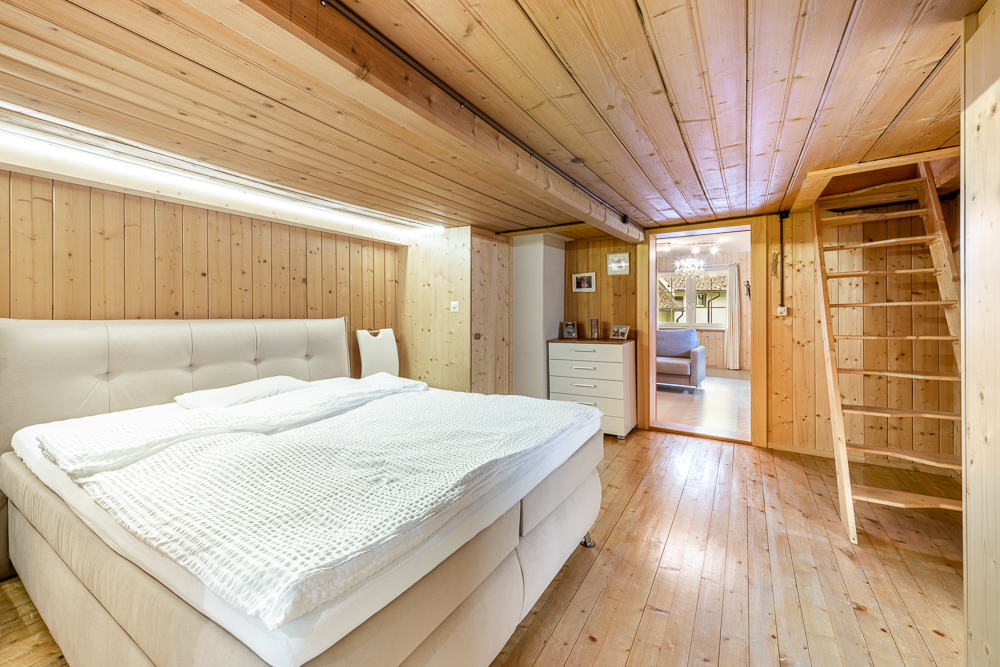 Holzvertäkeltes Schlafzimmer mit Bett und Leiter