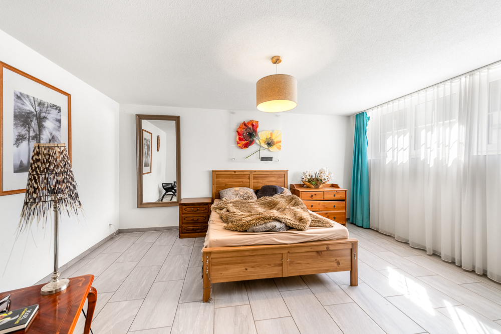 Helles Schlafzimmer mit Holzbetten und großer Fensterfront