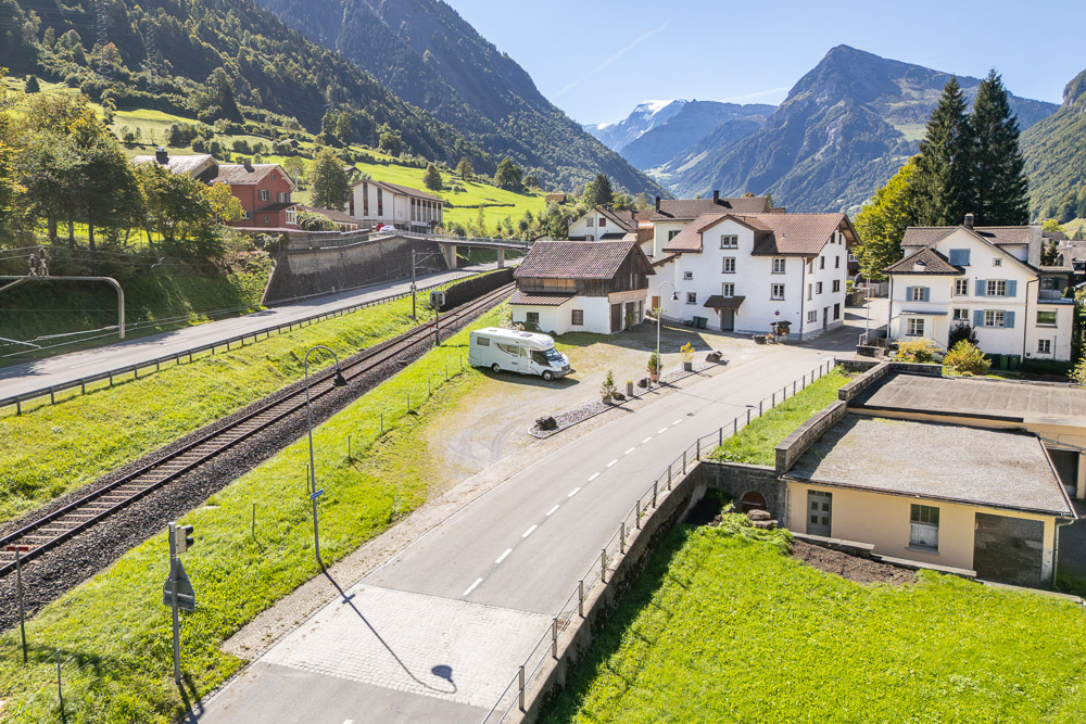 Bergdorf mit Bahnlinie und Alpenpanorama