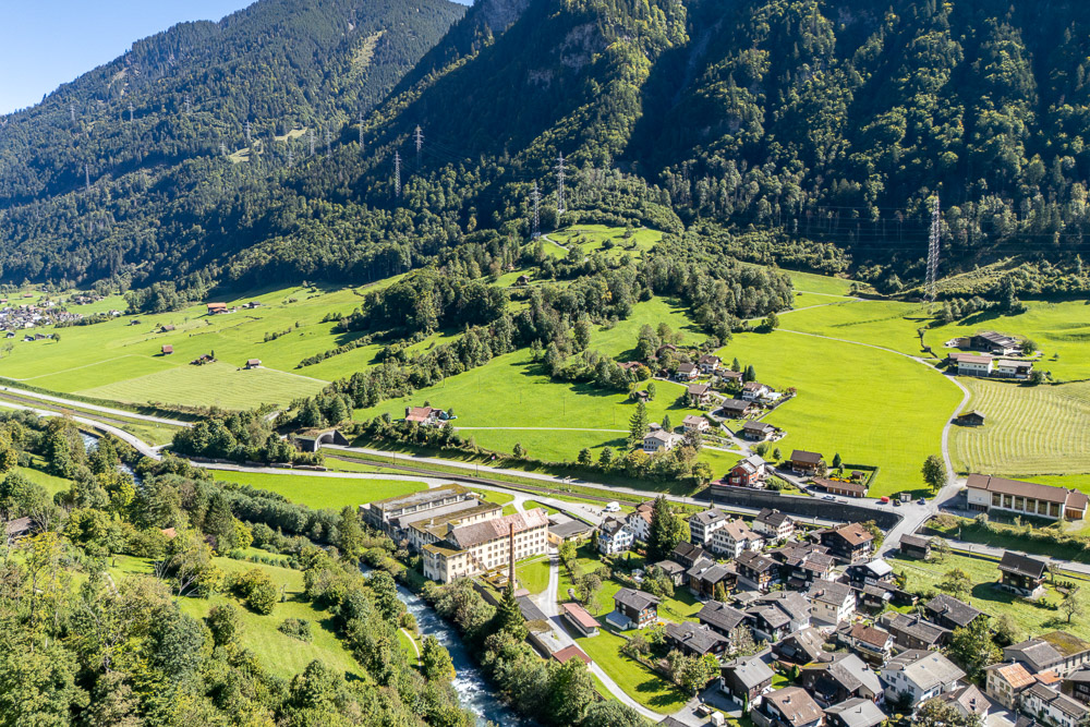 Luftaufnahme eines alpinen Tals mit Dorf und Fluss