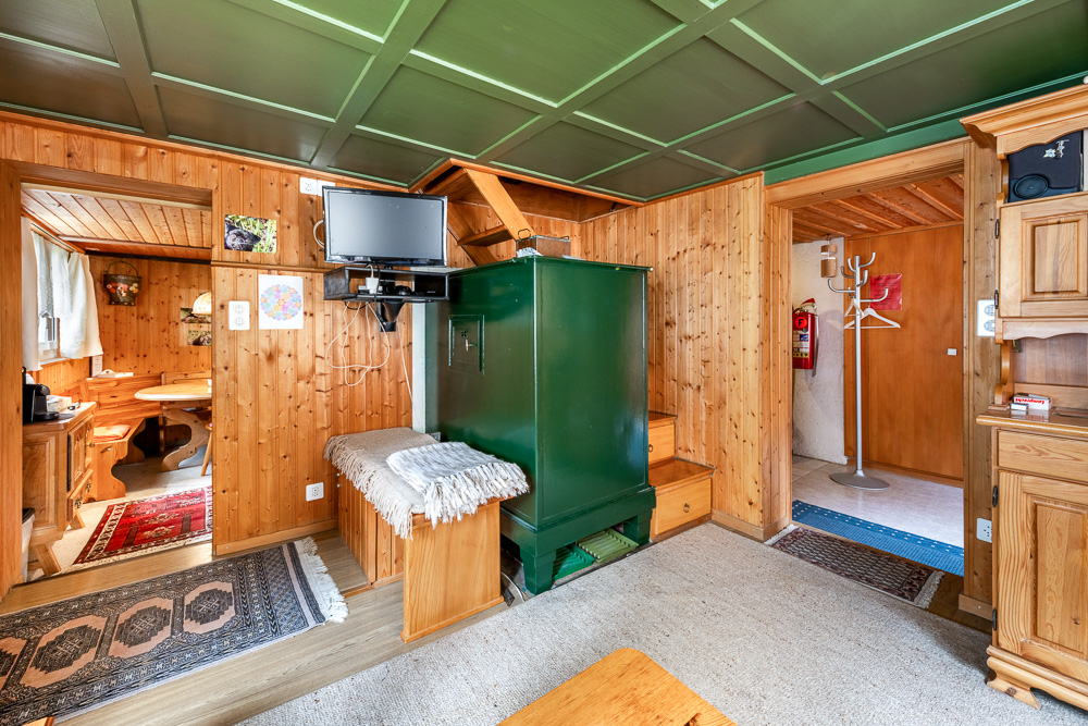 Holzverkleideter Innenraum mit grünem Ofen