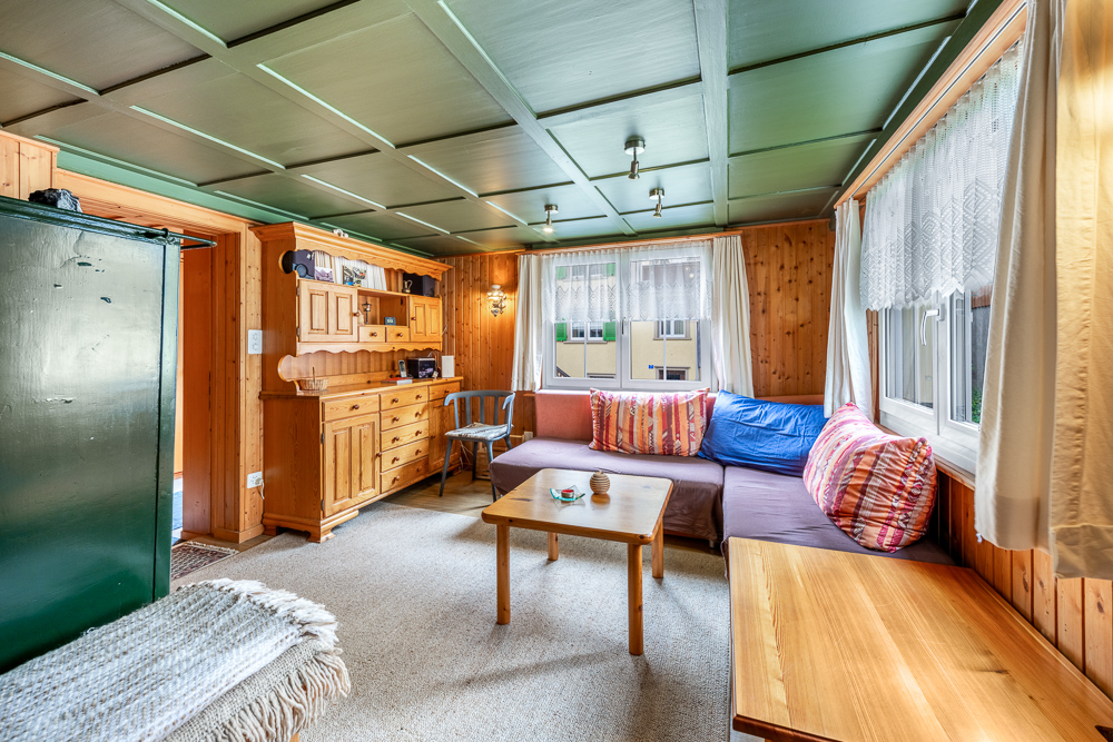 Gemütliches, holzverkleidetes Wohnzimmer mit großen Fenstern
