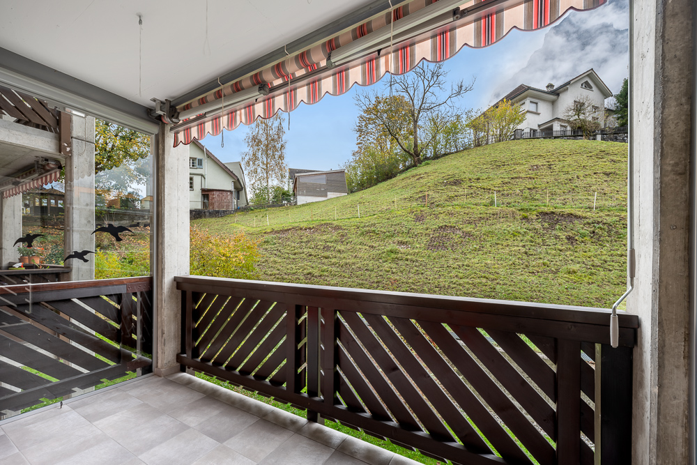 Überdachter Balkon mit Blick auf grüne Hanglage