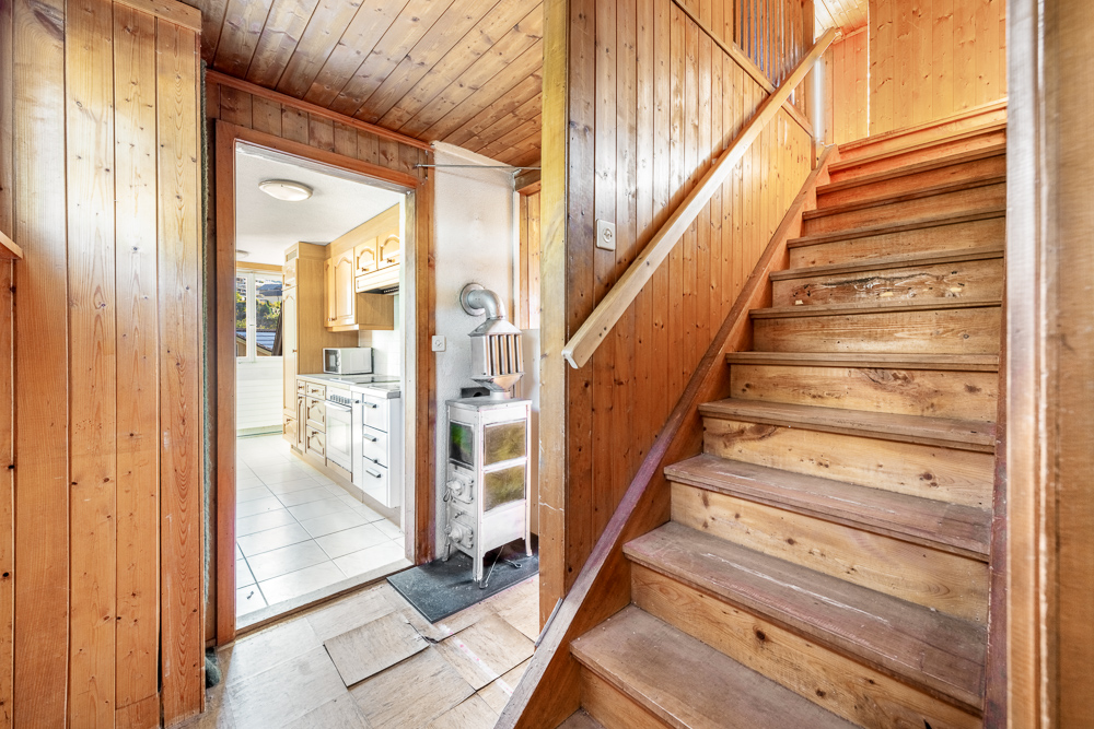 Holzgetäfelter Flur mit Treppe und Blick in die Küche