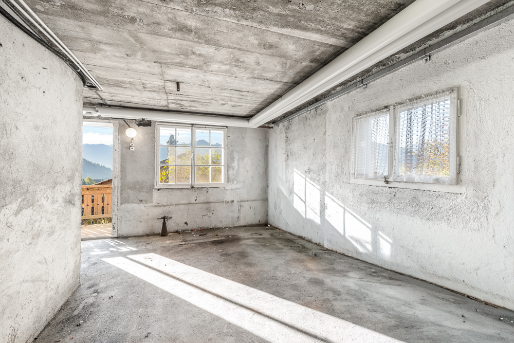 Unrenovierter Innenraum mit Betonwänden und Fenstern