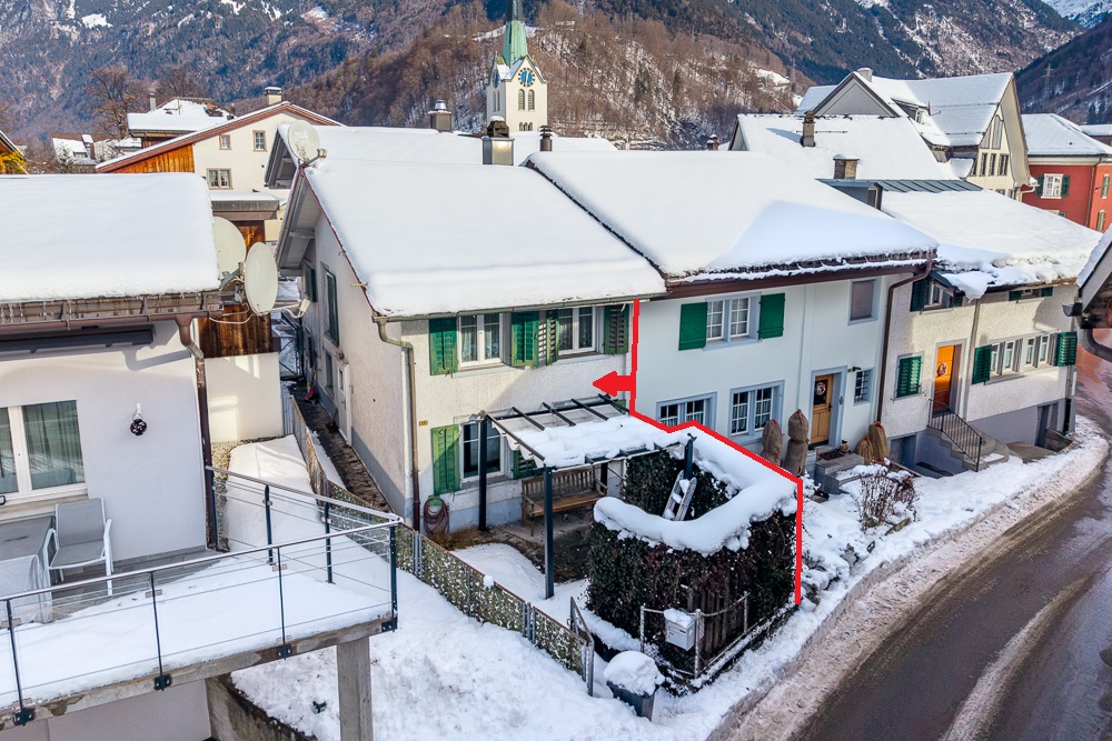 Verschneite Reihenhäuser mit Blick auf ein Bergdorf