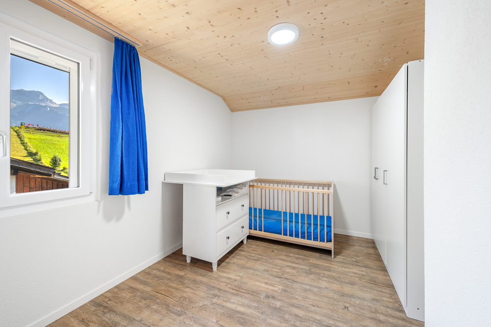 Hell eingerichtetes Kinderzimmer mit Bergblick