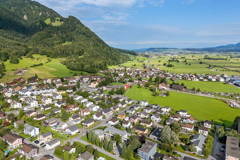 Luftaufnahme einer Alpen- oder Tallandschaft mit Siedlung