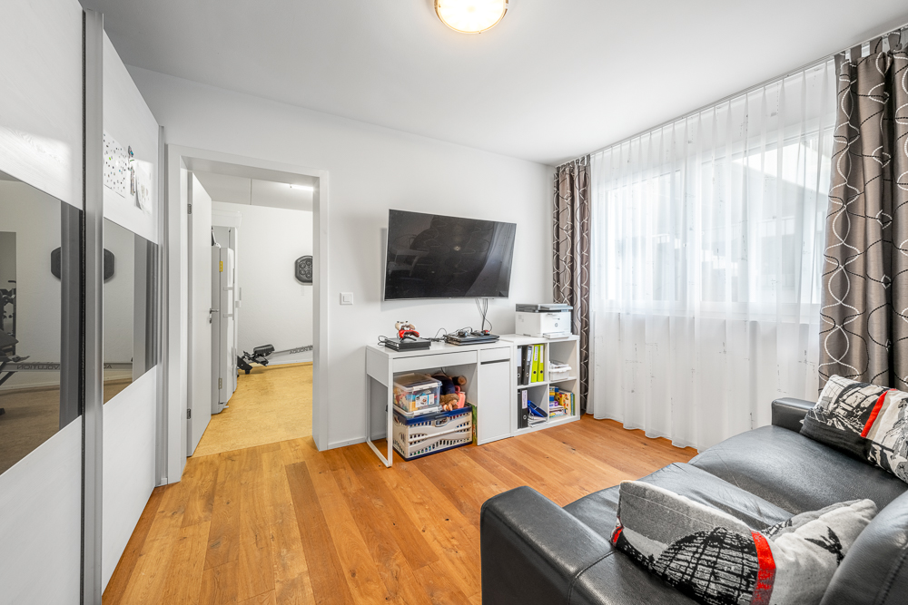 Wohnzimmer mit Fernseher und Fensterfront