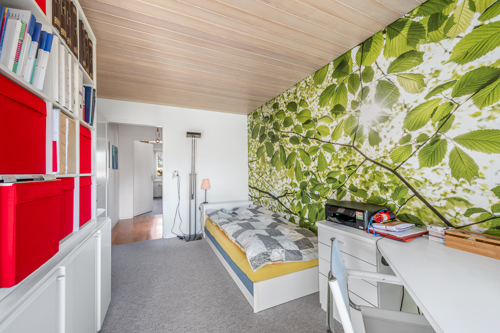 Hell eingerichtetes Schlafzimmer mit Naturmotiv-Wandgestaltung