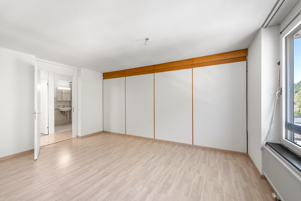Leeres Schlafzimmer mit Einbauschrank und Blick ins Bad