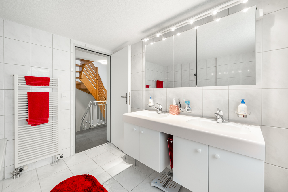 Modernes Badezimmer mit Doppelwaschtisch und rotem Akzent
