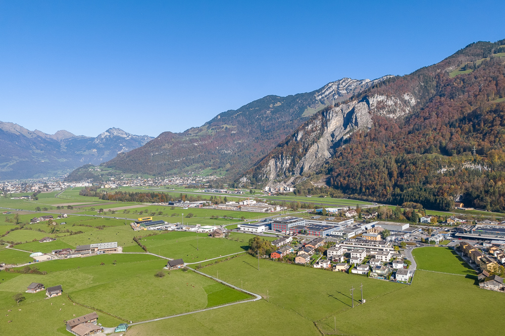 Luftaufnahme eines alpinen Tals mit Ortschaft und Bergen