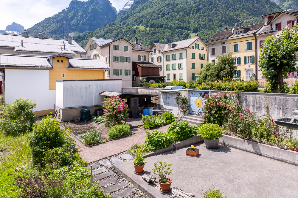 Blick auf einen begrünten Innenhof mit Bergkulisse