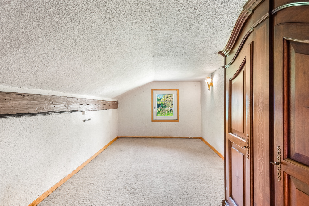 Dachgeschosszimmer mit Schrank und kleinem Fenster